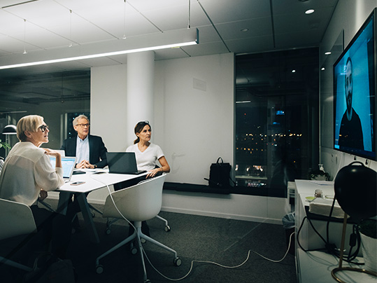 Three people in a conference room attending a meeting