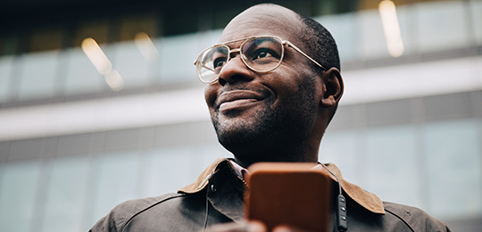 Person with glasses smiling and holding their phone