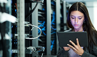 businesswoman in a server room looking at a tablet